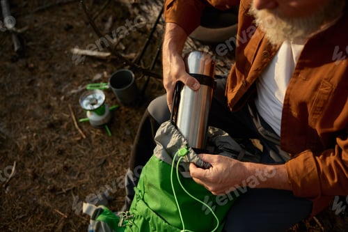 Preview: Travel adventure on nature, closeup view on man hiker putting thermos in bag