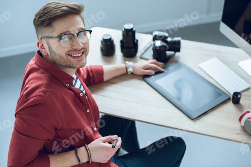 Preview: Happy freelancer man sitting by working table with graphic tablet