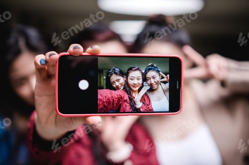 Preview: Group of female friends taking a selfie together with a mobile phone. Friendship concept.