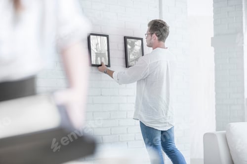 Preview: Man hanging pictures in room