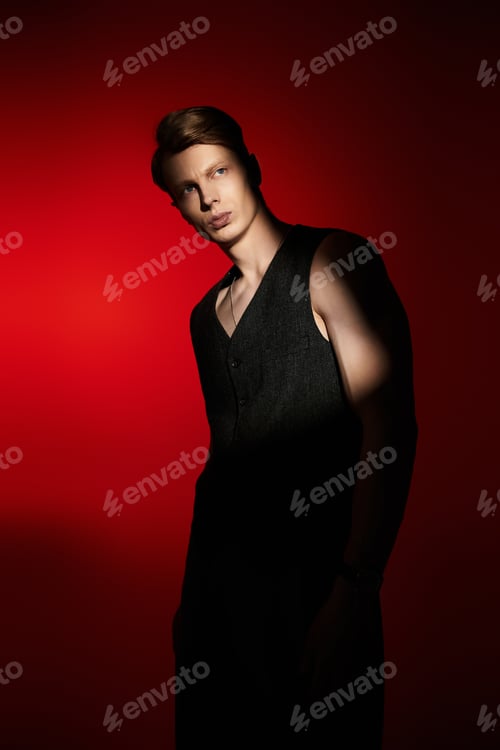 Preview: Young man embodies modern masculinity with captivating presence against a striking red backdrop