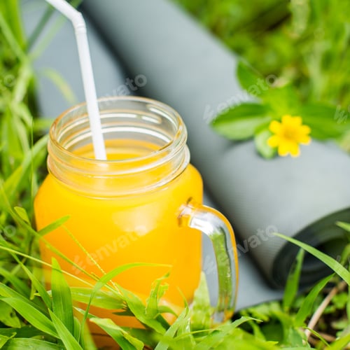 Preview: Fresh orange juice and yoga mat on the grass