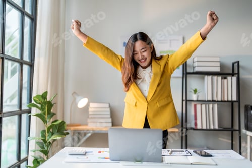 Preview: Happy asian businesswoman celebrating success raising arms working from home office