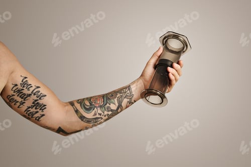 Preview: Closeup of tattooed man's hand holding aeropress