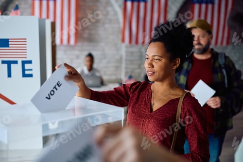 Preview: Black woman inserting her ballot into a box while voting during US elections.