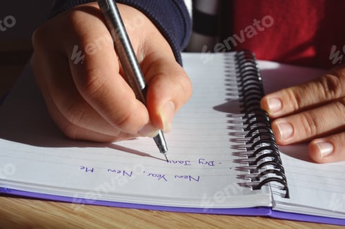 Preview: Millennial woman writing out a list New Year Resolutions