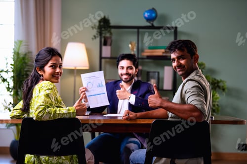 Preview: Young Indian husband and wife analyzing financial reports with planner in office