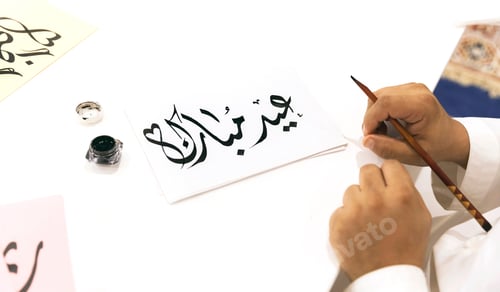Preview: Arabic calligraphy’Eid Mubarak’, hands of the artist in frame