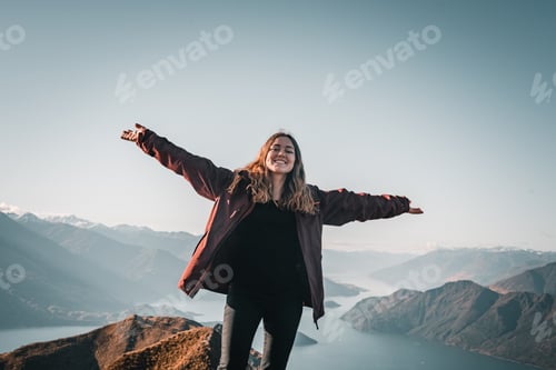Preview: blonde caucasian girl in coat and black pants smiling at camera happy and content with arms
