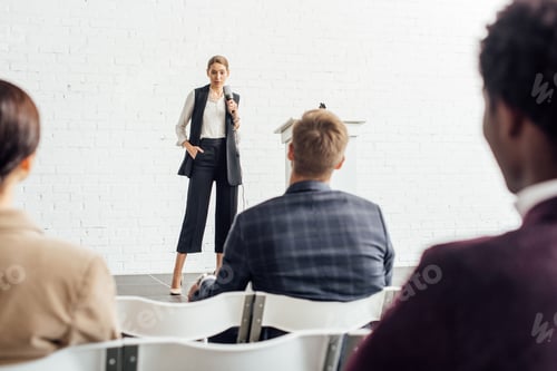Preview: attractive businesswoman holding microphone and talking during conference in conference hall