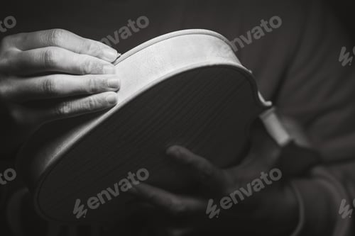 Preview: violin maker luthier hands roughing the edges of a raw blank violin with sandpaper