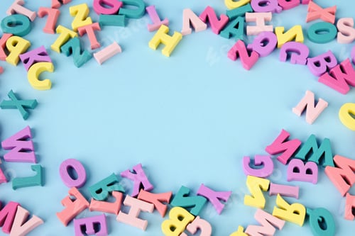Preview: Lots of multicolored wooden letters scattered on a blue background. Copy space in center.
