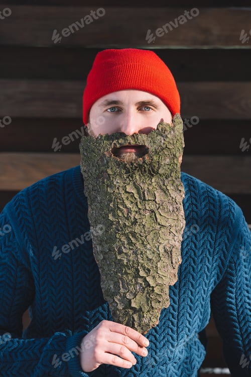 Preview: portrait of man with beard made of wood bark looking at camera outdoors
