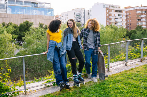 Preview: Young people enjoying afternoon with skateboard and roller skates in urban park