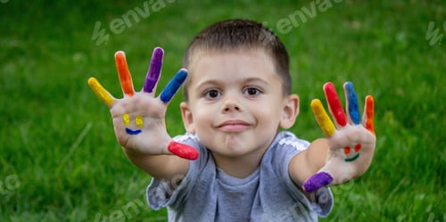 Preview: Children's hands in the colors of summer, a smile on the boy's palm
