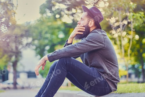 Preview: A man sits on a step over city park background.