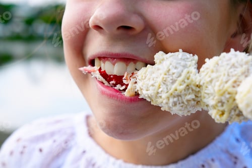 Preview: Beautiful girl eating a fresh red strawberry in white chocolate