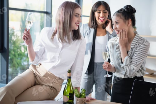 Preview: young multiethnic businesswomen smiling and drinking champagne at office