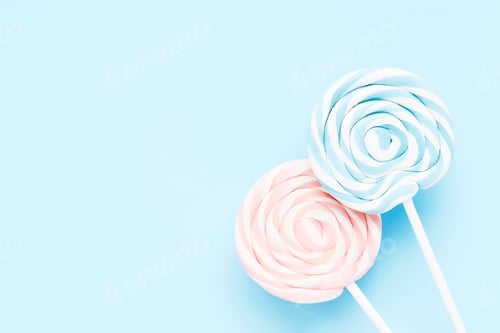 Preview: Pink and blue lollipops on a white stick on a light blue background. Top view, copy space