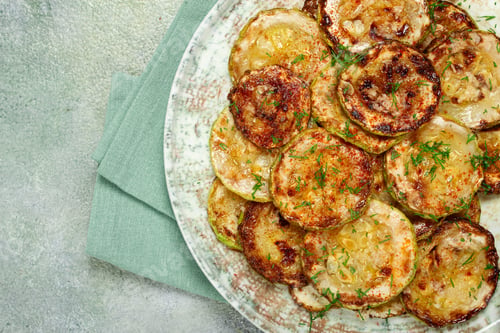 Preview: fried zucchini, cut into rings, with garlic and herbs, on a plate, top view, homemade, no people,