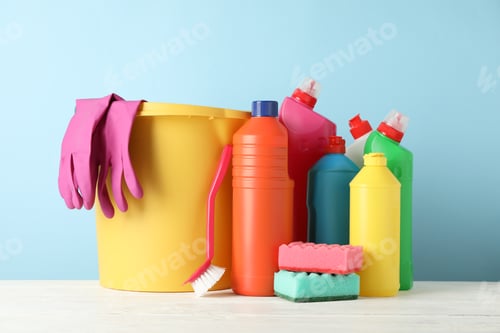Preview: Bucket, bottles with detergent and cleaning supplies on blue background, space for text