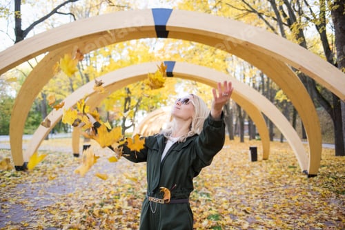 Preview: woman throws autumn maple yellow leaves in park in nature outdoor