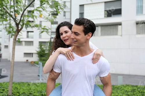 Preview: Totally in love. A young guy smiling while piggybacking his girlfriend out in the street.