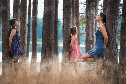 Preview: A group of people communing with nature, and leaning against tall straight trees in woodland.