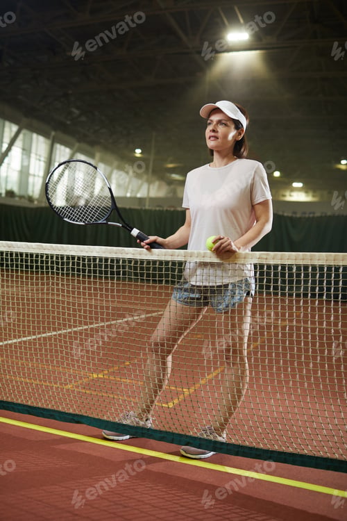 Preview: Female player standing by tennis net