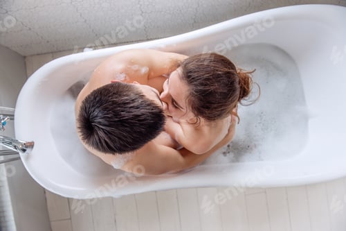 Preview: Close-up portrait, top view of a couple face to face in a bubble bath. The concept of tactility
