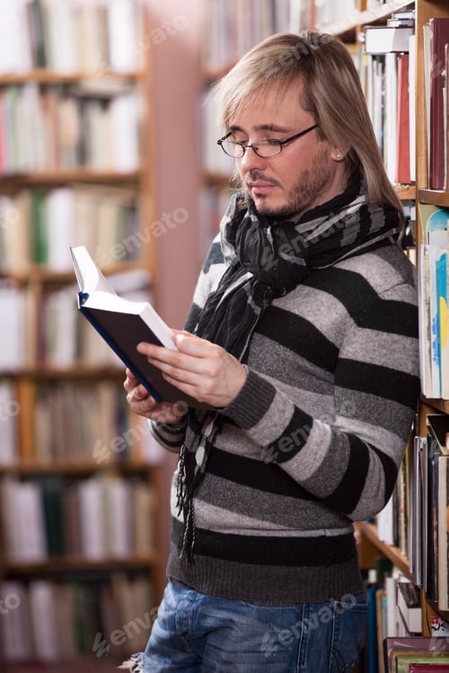 Preview: Handsome man reading book in library