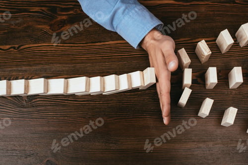 Preview: top view view of man preventing wooden blocks from falling at table