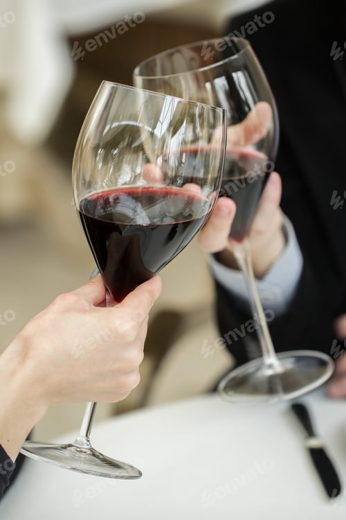 Preview: Man and woman drinking red wine. In the picture, close-up hands with glasses.