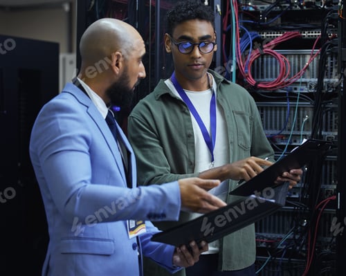Preview: Cropped shot of two male IT support agents working together in a dark network server room