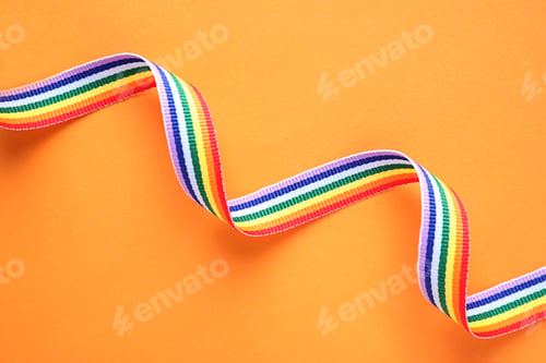 Preview: Bright rainbow ribbon on color background, top view. Symbol of gay community