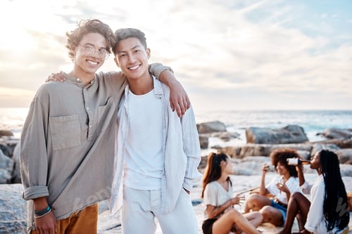 Preview: Portrait of two attractive young men standing together on the beach. Asian male and his best friend