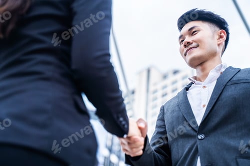 Preview: Asian businessman making handshake in the city building in the background.