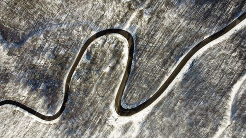 Preview: Aerial view of a winding road in a forest covered in snow