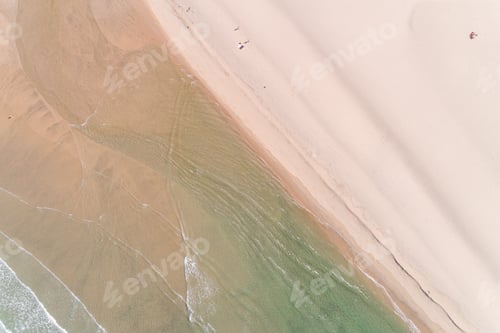 Vorschau: Drohnen-Luftaufnahme der Küste eines Strandes mit wenigen Menschen am Morgen, entspannte Zeit im Sommer