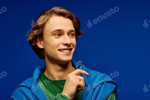 Preview: Fashionable young man showcasing modern style against a vibrant blue backdrop