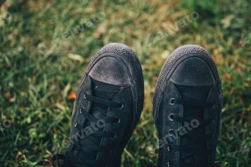 Preview: Dirty black sneakers shoes on grass