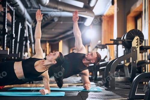 Preview: Cheerful young couple training core together indoors