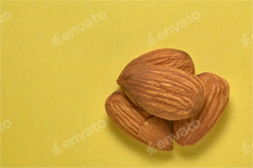 Preview: Close-up of a group of almonds on a yellow background.