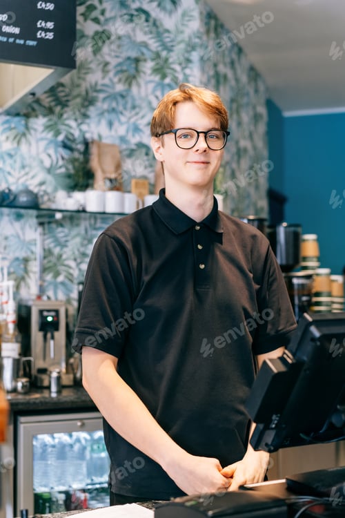 Preview: Young waiter serving customer at cash point in cafe. Man working with POS terminal. Cashier, barista