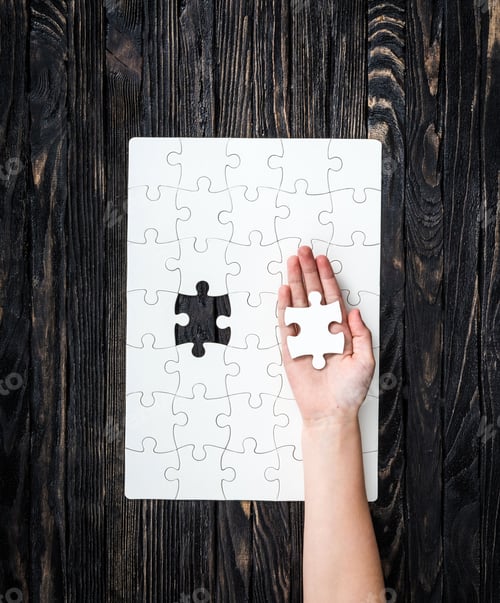 Preview: hand with the last piece of white uncomleted puzzle