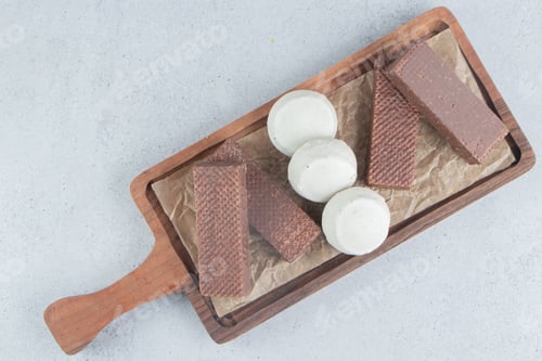 Preview: Chocolate wafers and cookies bundled on a wooden tray on marble background