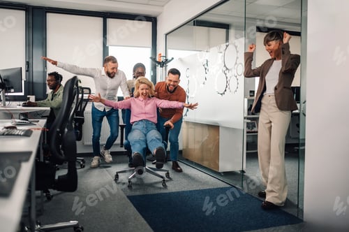 Preview: Business team having fun pushing colleague on office chair