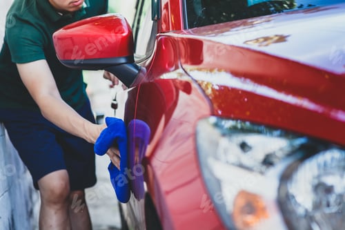 Preview: Young man washing and wiping a car in the outdoor