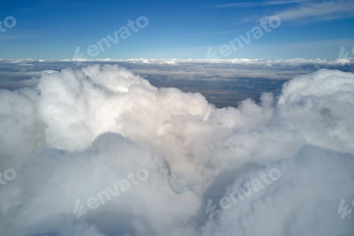 Preview: Aerial view from airplane window at high altitude of earth covered with white puffy cumulus clouds