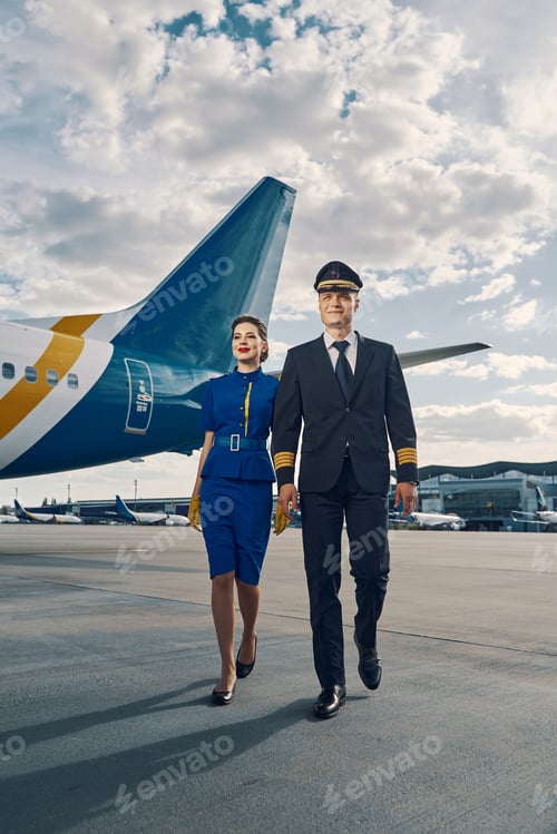 Preview: Smiling female flight attendant and an airplane pilot going ahead